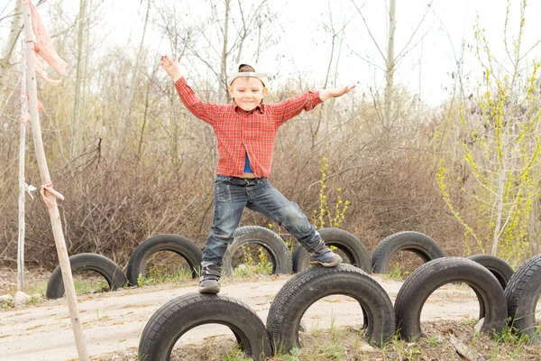 Schattige kleine jongen op oude autobanden in evenwicht — Stockfoto