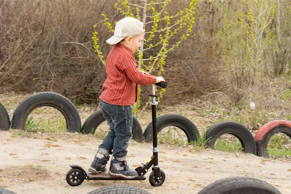 Niño pequeño montando su scooter en un carril de tierra — Foto de Stock