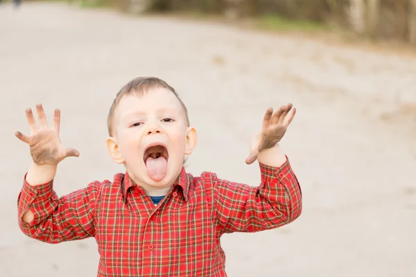 Speelse kleine jongen zijn tong uitsteekt — Stockfoto