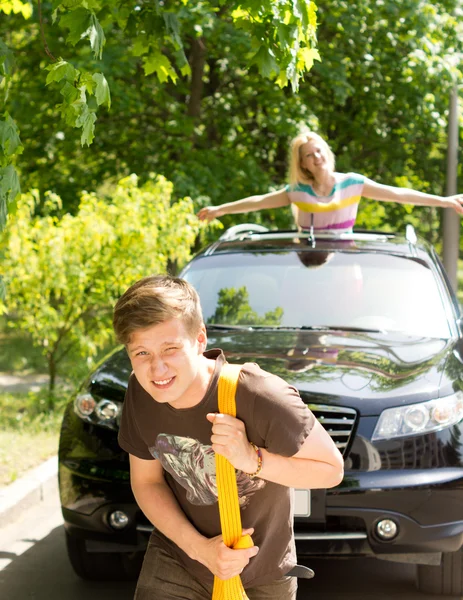 Handsome young man towing a car — Stock Photo, Image