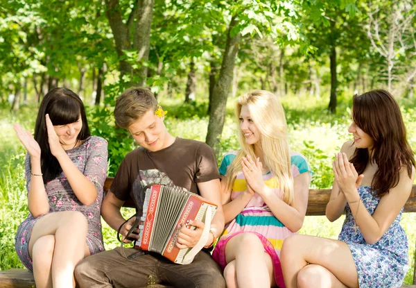 Friends enjoying music played on a concertina — Stock Photo, Image