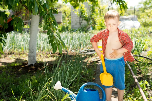 Liten pojke med en spade i trädgården — Stockfoto