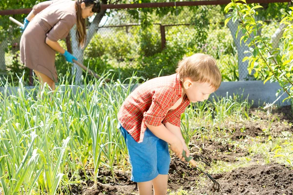 Liten pojke arbetar med sin mamma i trädgården — Stockfoto