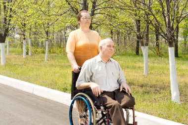Amputee being taken for a walk in a wheelchair clipart