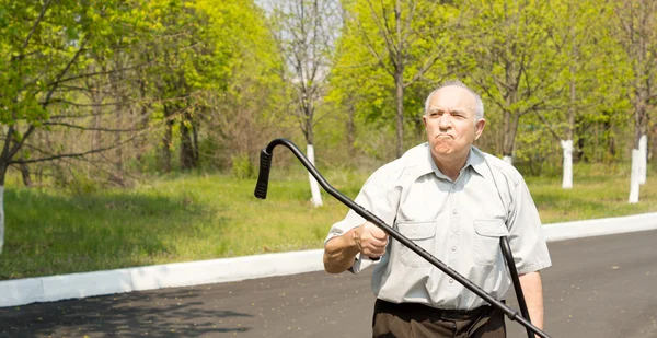 Elderly man waving his crutch in the air — Stock Photo, Image