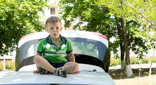 Kleiner blonder Junge sitzt auf dem Dach eines Autos — Stockfoto