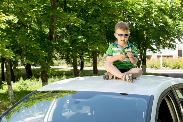 Jeune garçon assis sur le dessus d'une voiture jouant — Photo