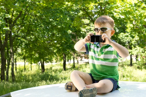 Pojke på en bil som fotograferar med en telefon — Stockfoto