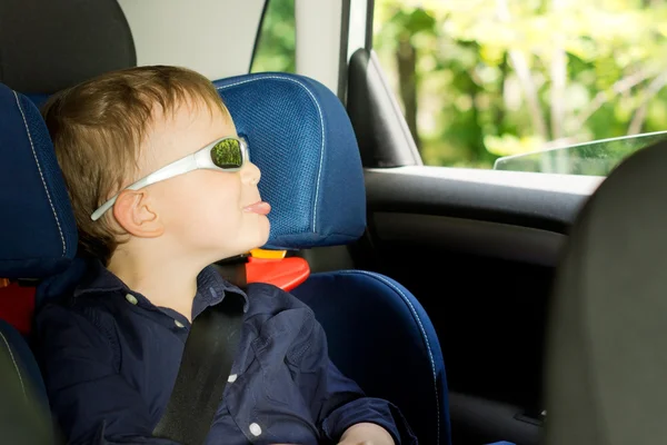 Playful small boy sitting in a child car-seat — Stock Photo, Image