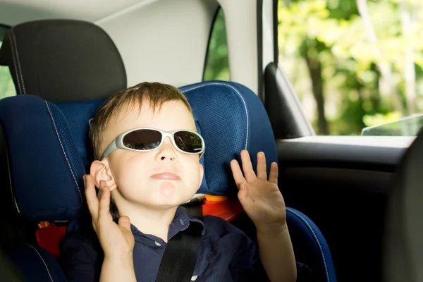 Niño pequeño juguetón sentado en un asiento de coche para niños —  Fotos de Stock