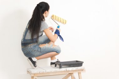 Duvarı boyayan genç bir kadın