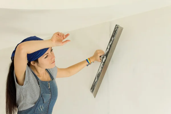 Tired woman wallpapering a wall — Stock Photo, Image