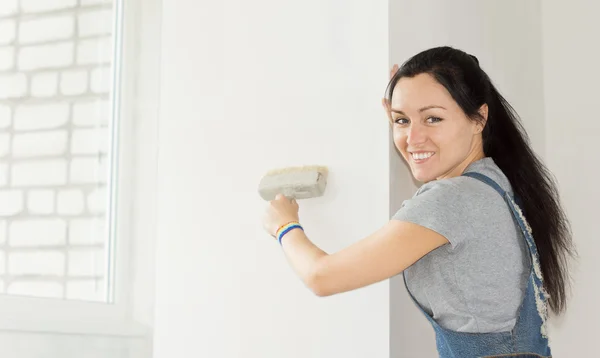 Donna sorridente che dipinge una sezione di muro — Foto Stock