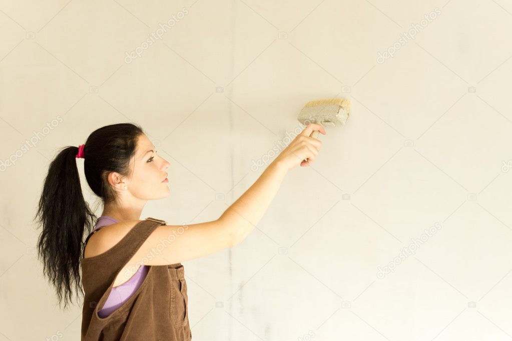 Young attractive woman decorating walls