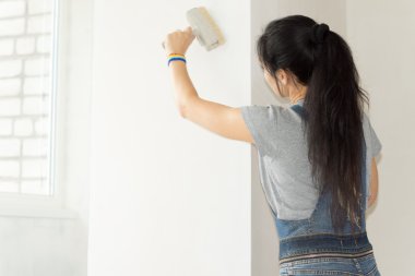 Kadın duvarı boyuyor.