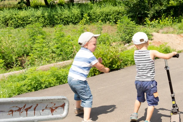 Двоє маленьких хлопчиків грають з скутером — стокове фото