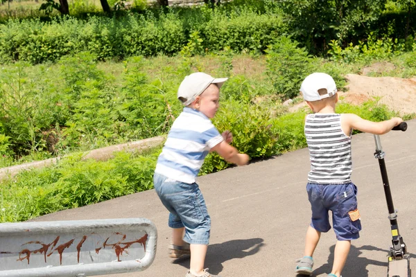 Två små pojkar som leker med en skoter — Stockfoto