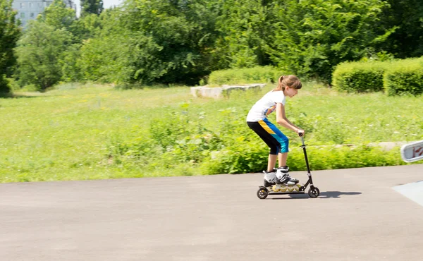 Meisje paardrijden een scooter in haar roller blades — Stockfoto