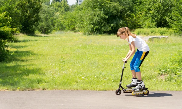 Jovem em uma scooter em patins — Fotografia de Stock