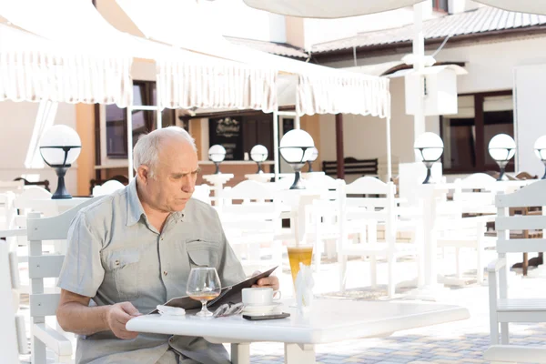 Пожилой человек проверяет счета в кафе — стоковое фото