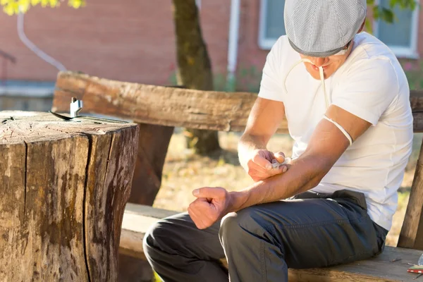 Addicted man injecting his left arm intravenously — Stock Photo, Image