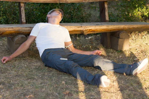 Utilisateur d'héroïne couché appuyé sur un banc — Photo