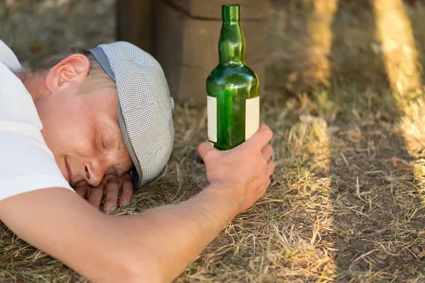 Bezdomny pijany mężczyzna śpi na ziemi — Zdjęcie stockowe