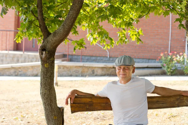 Man zittend op een bankje in het park in een zonnige dag — Stockfoto