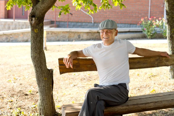 Homme assis sur un banc dans une journée ensoleillée de l'été — Photo