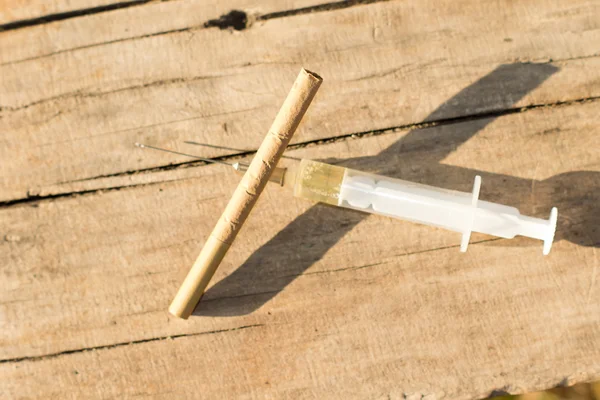Um cigarro e uma seringa cheios de uma dose — Fotografia de Stock