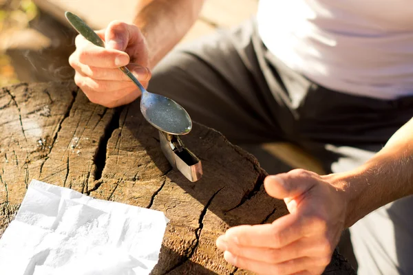 Manos de un hombre calentando drogas solubles en una cucharadita — Foto de Stock