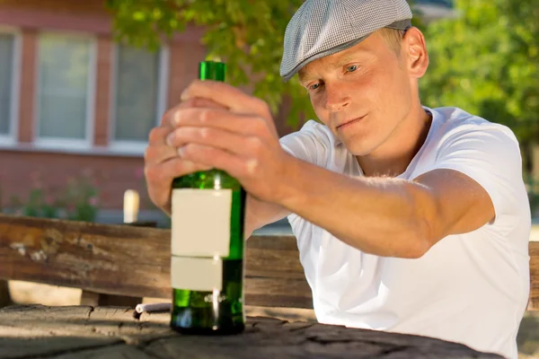 Uomo depresso con in mano una bottiglia di bevanda — Foto Stock