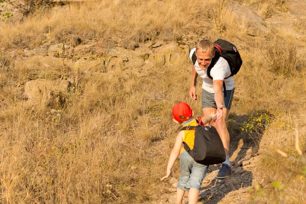 Giovane ragazzo scalare una montagna con suo padre — Foto Stock