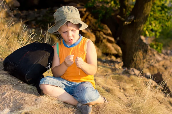 Young boy sitting on the ground with a rucksack — Stock Photo, Image