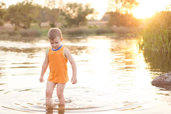 Niño pequeño vadeando en un lago al amanecer — Foto de Stock