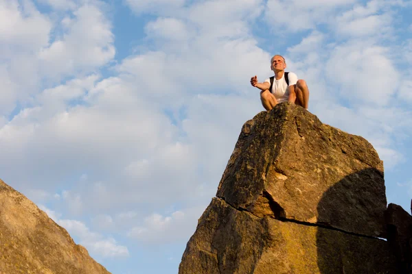 Homme assis sur un rocher élevé — Photo