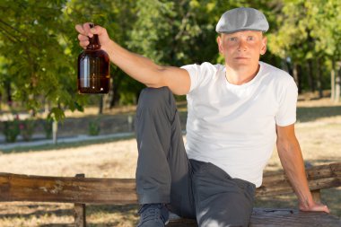 bir şişe ile parkta yalnız alkollü oturma