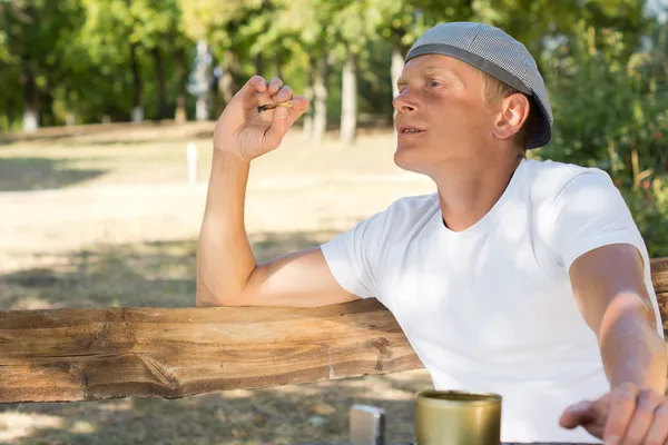 Man sitting smoking in the park — Stock Photo, Image