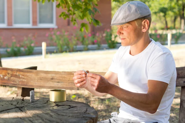 Caucasian man rolling a cigarette in a summer day — Stock Photo, Image