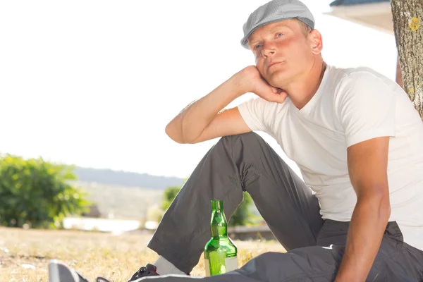 Homem deprimido sentado com uma garrafa de vinho branco — Fotografia de Stock