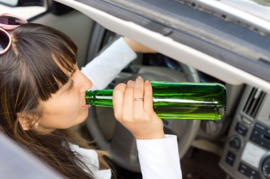 Woman drinking alcohol while driving a car clipart