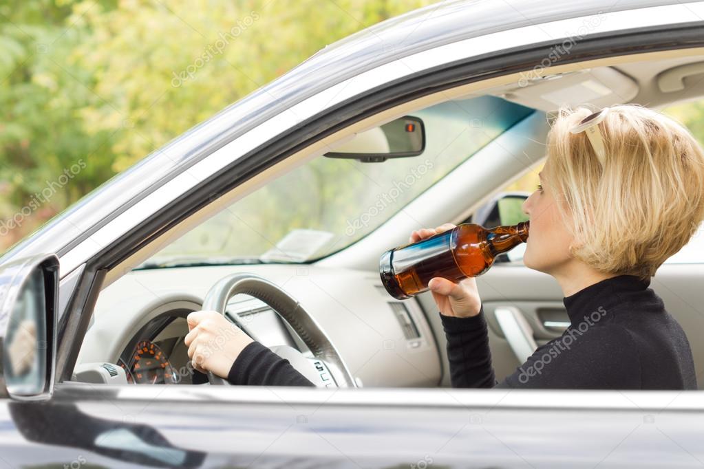 Woman driving along drinking alcohol