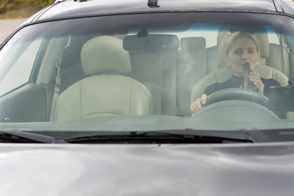 Kvinnliga föraren dricka alkohol i bilen — Stockfoto