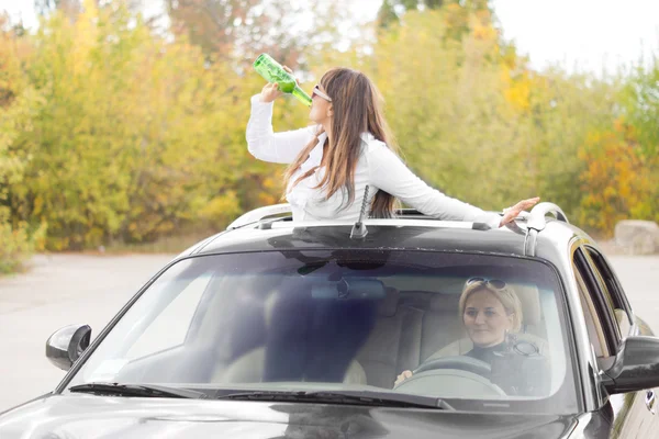 Woman standing up through a sunroof drinking — Stock Photo, Image