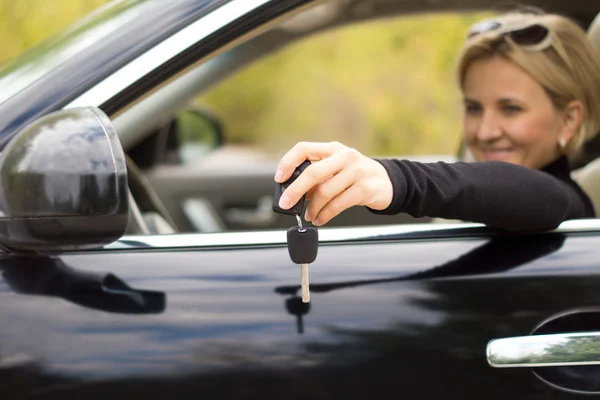 Женщина-водитель с ключами и новой машиной — стоковое фото