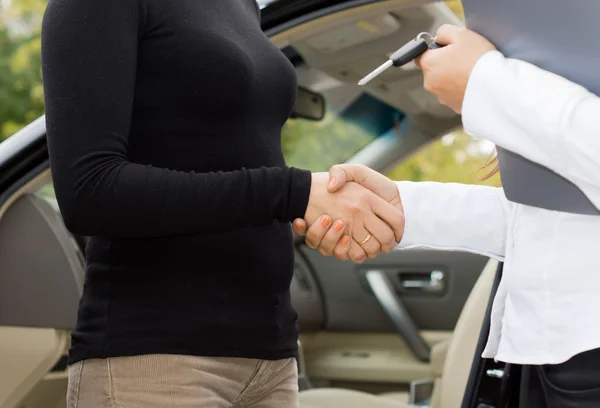 Women shaking hands on a car purchase — Stock Photo, Image