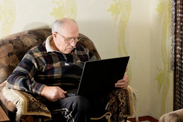 Uomo anziano seduto a lavorare sul suo computer portatile — Foto Stock