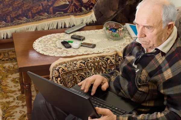 Homem sênior sentado trabalhando em um laptop — Fotografia de Stock