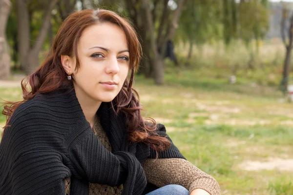 Young woman sitting outdoors in a park — Stock Photo, Image