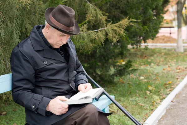 Disabled man on crutches reading in the park — Stock Photo, Image